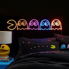 a neon sign above a bed in a dark room with pillows and blankets on it