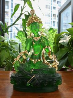 a green statue sitting on top of a wooden table