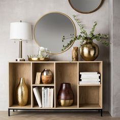 a shelf with books, vases and a mirror on it