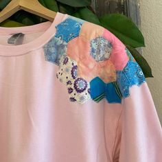 a pink shirt with patches and flowers on it