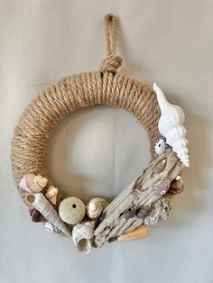 a wreath made out of driftwood and rope with shells on it hanging from the wall