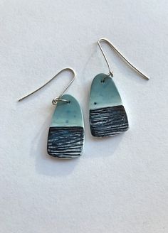 two blue and black earrings with silver hooks on a white surface, one is shaped like a rectangle