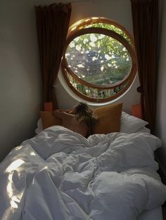 a woman is laying in bed looking out the window