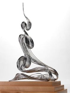 a metal sculpture sitting on top of a wooden block