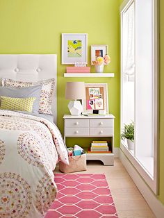 a bedroom with green walls and white bedding, pink rugs and pictures on the wall