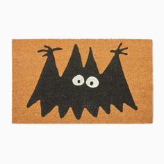 a door mat with two black bats on it and one has eyes, nose and legs