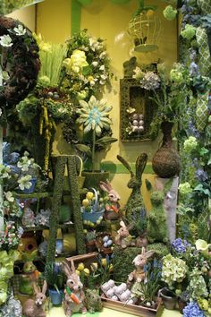 an assortment of fake flowers and plants in a display case at a flower shop,