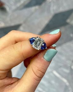 a woman's hand holding a diamond and blue sapphire engagement ring with diamonds on it