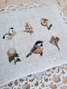 a close up of a piece of cloth with birds and flowers on it, sitting on a doily