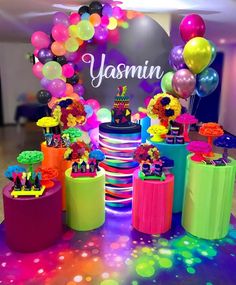 a table topped with lots of colorful cakes and balloons