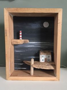 a wooden shelf with a small house in the middle and a lighthouse on it's side