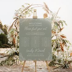 a welcome sign with flowers and greenery on the beach