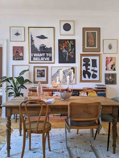 a dining room table with chairs and pictures on the wall in front of it,