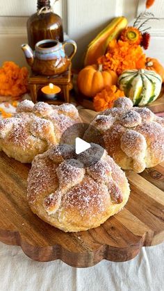 some sugar covered donuts are on a wooden platter with pumpkins in the background