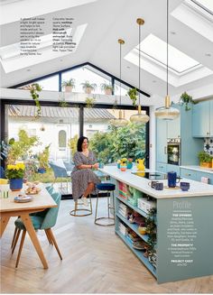 a woman sitting at a table in a kitchen with skylights above her and plants hanging from the ceiling