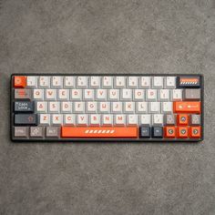 an orange and white keyboard sitting on top of a gray floor next to a black mouse