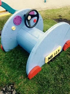 a blue toy airplane sitting on top of a green grass covered park area next to a playground