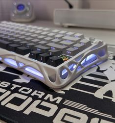 a computer keyboard sitting on top of a black and white mouse pad with blue lights