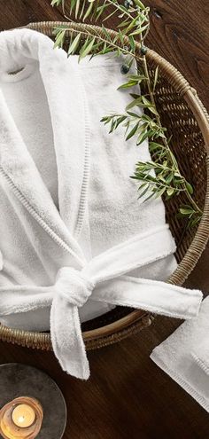 a white robe sitting on top of a wooden table next to a candle and napkin