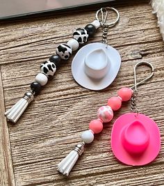 a pink hat and tassel keychain sitting on top of a wooden table