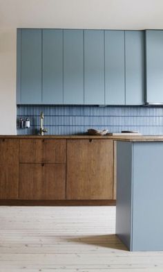 an empty kitchen with blue cabinets and wood flooring on the walls, along with a wooden countertop