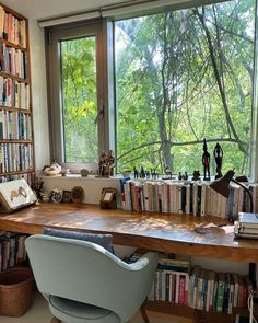 a chair sitting in front of a book shelf filled with lots of books next to a window