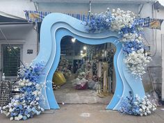 a blue arch decorated with white and blue flowers in front of a storefront entrance