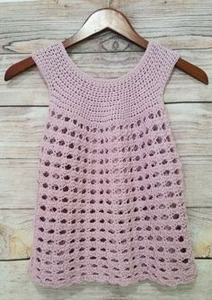 a pink crocheted top hanging on a wooden hanger with the text free pattern sunset shell crochet top