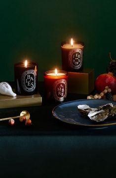 three candles are sitting on a table next to some fruit and other items that include oysters