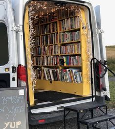 the back end of a van with bookshelves in it and a sign on the side