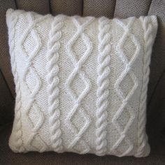 a white knitted pillow sitting on top of a couch