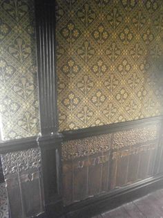 an ornate wallpapered room with wooden floors and walls in the background is sunlight coming through the window