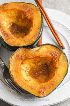 two acorn squash halves on a plate with cinnamon sticks and an orange napkin next to them