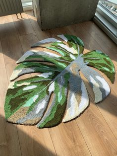 a green and white rug sitting on top of a wooden floor next to a window