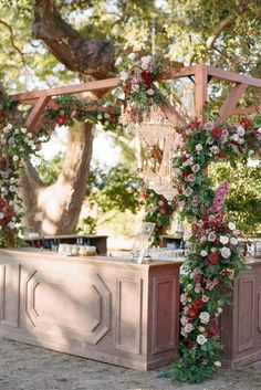 an outdoor bar decorated with flowers and greenery