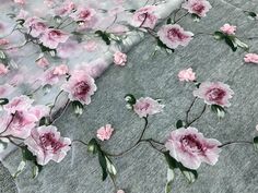 pink flowers on white fabric with green leaves and stems in the center, as well as grey background