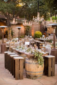 an outdoor dining area with wine barrels and chandeliers