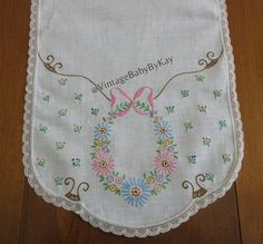 a white handkerchief with a pink bow and floral wreath on it, sitting on a wooden floor