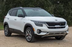 a white suv parked in front of some trees