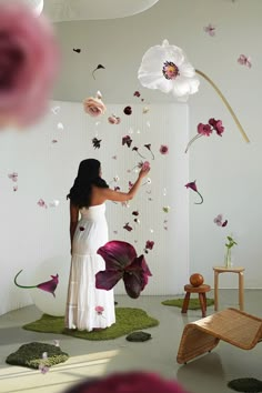 a woman standing in front of a wall with flowers on it and petals falling from the ceiling