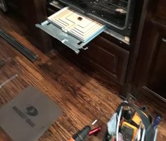 an open oven door with tools on the floor next to it