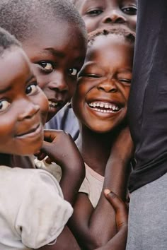 a group of children standing next to each other with their hands on the back of them