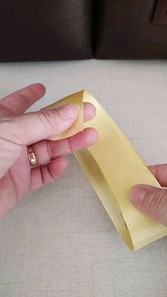 two hands are holding a piece of paper that is folded into the shape of a rectangle