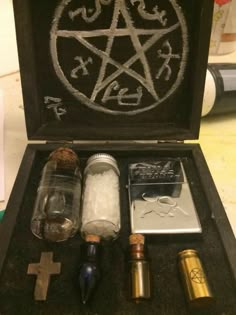 an open box with various items in it on a table next to a cross and pen