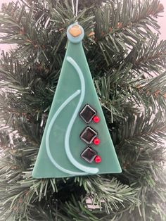 a glass christmas tree ornament hanging from a pine tree with candy in it