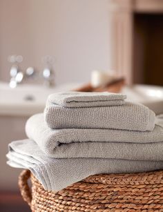 stack of folded towels sitting on top of a wicker basket