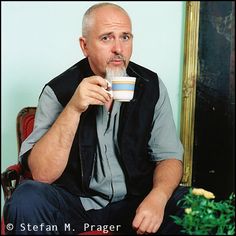 a man sitting in a chair drinking from a cup