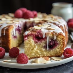 a piece of cake on a plate with raspberries and almonds