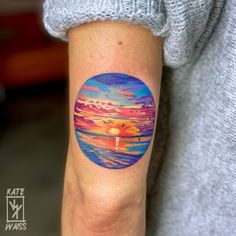 a woman with a colorful sunset tattoo on her arm