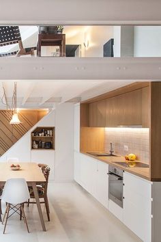 an open kitchen and dining area with stairs leading up to the second floor in this modern home